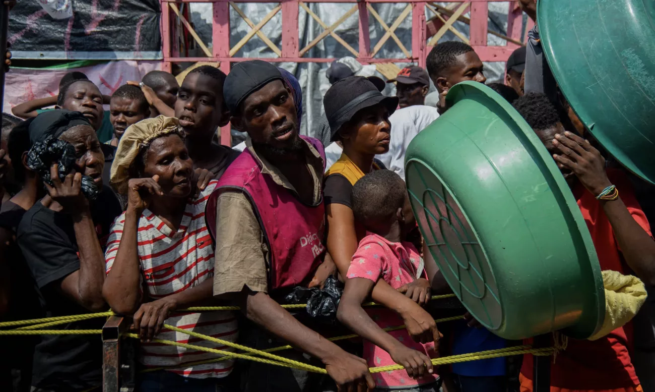 Haitililer, 30 Eylül 2024'te Port-au-Prince'teki Lycée Marie Jeanne'de yerinden edilmiş kişiler için kurulan bir kampta yiyecek kuyruğunda bekliyor. Fotoğraf: Clarens Siffroy/AFP/Getty Images